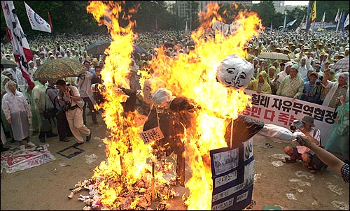 '한·중 마늘 비밀협상 및 한·칠레 자유무역협정 밀실협의 규탄 농민대회'에 참가한 농민들이 '외교통상부' '한중 마늘협상' 'WTO'가 적힌 허수아비를 불태우고 있다. 